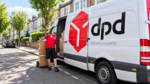 DPD delivery worker standing beside a branded electric delivery van outside a distribution warehouse.